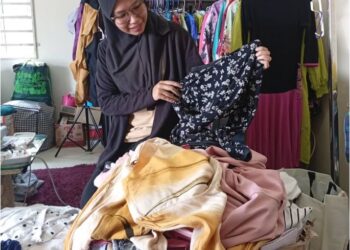 NORADIAH Ismail melihat sebahagian pakaian terpakai yang dikumpulkan hasil sumbangan orang ramai. – UTUSAN/ERMA YUSNIDA JUSOH