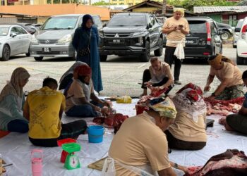 SUAIBAH Harun (berdiri, kiri) meninjau kerja-kerja pemotongan daging korban sebelum diagihkan kepada golongan memerlukannya di Primula Beach Hotel, Kuala Terengganu.