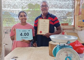 M. Sandhya Devi bersama bapanya menunjukkan keputusan cemerlang STPM diperolehnya ketika ditemui di Pasar Besar Tampin hari ini.-UTUSAN/NOR AINNA HAMZAH