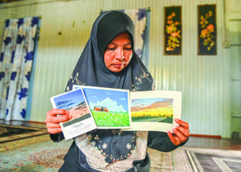 JUARIAH Abd. Rahman menunjukkan tiga lukisan Muhammad Mustaqim Rosdee yang seolah-olah menggambarkan pengakhiran hidupnya di Kampung Telaga Nibong, Besut, Terengganu. – UTUSAN/PUQTRA HAIRRY