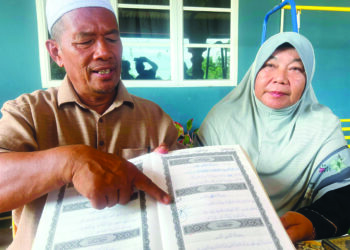 KAMARIAH Abdul Latif bersama suaminya, Azman Mohammad menunjukkan naskhah kitab hafazan al-Quran tulisan tangan Nurly Shahirah di Kampung Gong Pasir, Besut, Terengganu. – UTUSAN/TOREK SULONG