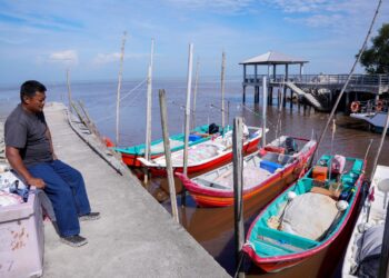 NORHAKIM Mohamad Yasin melihat deretan bot nelayan pantai di Pantai Batu 23, Sungai Nibong, Sekinchan, Selangor. - MINGGUAN/SADDAM YUSOFF