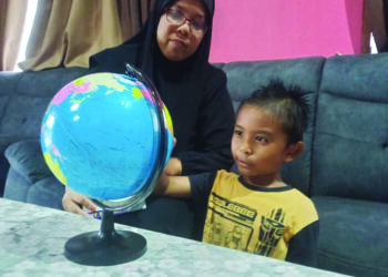 MUHAMMAD Umar Ziqri Mohd. Khairul Azuan melihat peta dunia dengan ditemani Zuliyani Yunus di Kampung Pasir Dula, Hulu Terengganu. - UTUSAN / NOOR HAYATI MAMAT