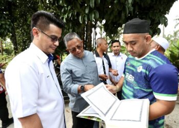 BESUT 12 JUN 2025 - HASSAN Basri Awang Mat Dahan (tengah) melihat al-Quran tulisan tangan Nurly Shirah Azamn yang ditunjukkan abang Allahyaryam, Mohd. Najmuddin Azman di Kampung Gong Pasir, Kerandang, Besut Terengganu. - UTUSAN/TOREK SULONG