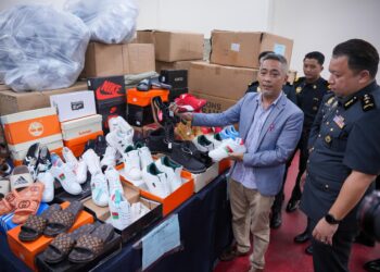 MOHD. Sabri Seman (kiri) bersama Mohd. Shahran Mohd. Arshad menunjukkan sebahagian daripada 14,300 pasang selipar dan kasut tiruan berjenama berjumlah hampir RM400,000 yang dirampas dalam satu serbuan pada 16 Jun ke atas lapan buah stor penyimpanan yang beroperasi di sebuah kompleks pemborong bersebelahan Jalan Tuanku Abdul Rahman. - UTUSAN/SADDAM YUSOFF