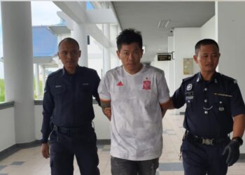 TAN Soo Kian diiringi anggota polis ketika dihadapkan ke Mahkamah Majistret Ayer Keroh, Melaka, atas pertuduhan memiliki pistol tiruan dan peluru ball bearing. - UTUSAN/ MUHAMMAD SHAHIZAM TAZALI