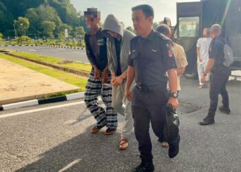 TERTUDUH (dua dari kiri) dibawa masuk ke mahkamah bagi menghadapi dua pertuduhan iaitu mengedar dan memasukkan dadah ke dalam badan di Kompleks Mahkamah Kangar, Perlis hari ini.- UTUSAN/ASYRAF MUHAMMAD