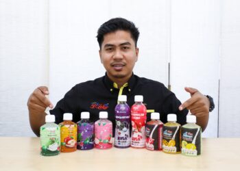 MUHAMMAD Ikmal Ahmad Zaki menunjukkan produk minuman berasaskan buah-buahan yang dihasilkan di kilangnya di Taman Lekir Maju di Lumut. - UTUSAN/MUHAMAD NAZREEN SYAH MUSTHAFA