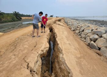 PENDUDUK menunjukkan ban penahan ombak yang runtuh di Bagan Sungai Tiang di Bagan Datuk, Perak. 
– UTUSAN/AIN SAFRE BIDIN