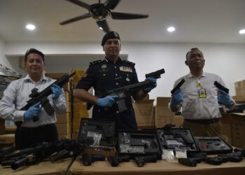 ZAIRULNIZAM Mohd. Zainuddin @ Hilmi (tengah) menunjukkan senjata api tiruan yang berjaya dirampas.
