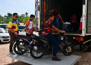 SUKARELAWAN Universiti Pendidikan Sultan Idris (UPSI) menurunkan motosikal milik mangsa kemalangan di Gerik, Perak untuk diserahkan kepada waris mereka  di Masjid Hadhari, Jertih, Besut, Terengganu. - UTUSAN/PUQTRA HAIRRY