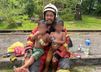 MOHD. Zulkifli Abd. Azis memangku dua beradik yang diselamatkan bersama rakan setugasnya dalam kebakaran di Taman Sri Kota, Kuala Kedah.
