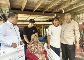 KHAIRUDIN Abu Hanipah (kanan) ketika menyerahkan sumbangan kepada Aziz Jaafar Yusof di Kampung Panchor di Bota hari ini. - UTUSAN/LIYANA RAMLI