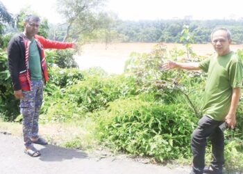 RAZAK Daud (kanan) dan Syahrulnizam Harun menunjukkan tapak kubur lama yang lenyap kesan hakisan tanah Sungai Pahang di Kampung Gintong, Jerantut, Pahang. - UTUSAN/SALEHUDIN MAT RASAD