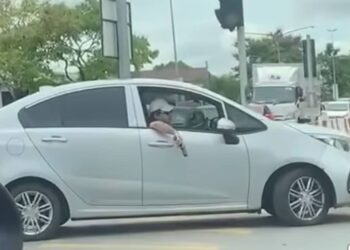 Tangkap layar dari video yang menunjukkan suspek memegang pistol tiruan ketika memandu di persimpangan Jalan Keretapi di Kuching, semalam.