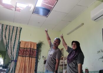 MOHD Sofian Ismail dan Noor Hazira Fauzi menunjukkan bumbung rumah yang rosak akibat ribut di Taman Serai Perdana, Bagan Serai hari ini. - UTUSAN/WAT KAMAL ABAS