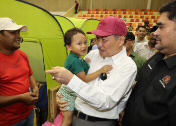 HAJIJI Noor mendukung kanak-kanak ketika melawat mangsa kebakaran sambil diiringi Timbalan Ketua Menteri Sabah, Datuk Ir Shahelmey Yahya.