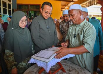 AHMAD Samsuri Mokhtar (dua dari kiri) melihat naskhah al-Quran tulisan tangan pelajar Universiti Pendidikan Sultan Idris (UPSI), Nurly Shahirah Azman, yang maut dalam kemalangan di Jalan Raya Timur-Barat (JRTB) berhampiran Tasik Banding, Gerik, 9 Jun lalu, di rumah arwah di Kampung Gong Pasir, Kerandang, Jertih, Besut, Terengganu. - UTUSAN/PUQTRA HAIRRY