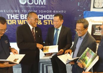 PANDAK Ahmad (dua, kiri) bertanyakan sesuatu kepada Mohd. Roslan Mohd. Tahir tentang buku 'Titian Perjalanan Sebuah Kehidupan' di Open University Malaysia Johor Bahru.