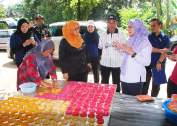 SHARMILA Mohamed Salleh memperkatakan sesuatu kepada Tuminah Kadi sewaktu melawat pembuatan kuih tradisional inang-inang di Kampung Paya Luboh, Tangga Batu, Melaka. - UTUSAN/AMRAN MULUP