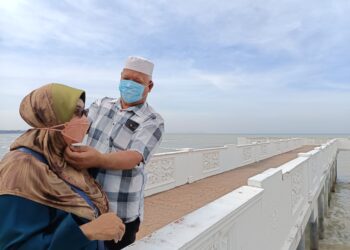MUHAMAD Azman Zakaria dan isterinya memakai pelitup muka susulan jerebu yang melanda kawasan Port Dickson sejak semalam.-UTUSAN/NOR AINNA HAMZAH
