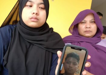 NUR Aina Tasmin Abdullah (kiri) di samping ibunya, Aniza Mohd Taib menunjukkan gambar abang kembarnya, Muhammad Armin yang meninggal dunia setelah terlibat kemalangan ketika ditemui di Hospital Baling.