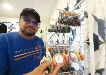 FIRDAUS Bentris menunjukkan produk pemegang kunci topi diperbuat daripada bahan kitar semula yang dijual di Kampung Air Puteri, Mersing.