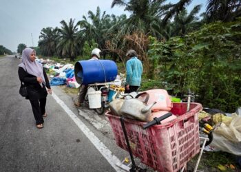 SITI Mastura Mohd. Salleh meninjau lokasi pembuangan sampah di tepi jalan utama di Kampung  Simpang Empat, Hutan Melintang, Bagan Datuk. – UTUSAN/AIN SAFRE BIDIN