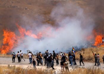 KOMUNITI Druze Syria berjalan merentasi asap gas pemedih mata yang dilepaskan tentera Israel ketika cuba menyeberangi pagar dawai berduri ke Bukit Golan berhampiran Majdal Shams. – AFP