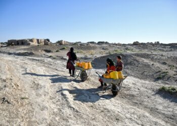 PENDUDUK Afghanistan membawa tong air menggunakan kereta sorong di sepanjang jalan di kampung Bolak yang dilanda kemarau, di daerah Chahar Bolak, wilayah Balkh. – AFP