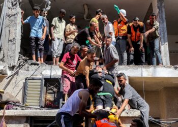 ORANG ramai membantu pasukan kecemasan menurunkan seorang wanita yang cedera selepas sebuah bangunan musnah dibedil tentera Israel di tengah Semenanjung Gaza, Palestin.– AFP