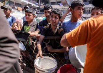 KANAK-kanak Palestin beratur sambil memegang periuk untuk menerima makanan dari dapur amal di Bandar Gaza, kelmarin. – AFP
