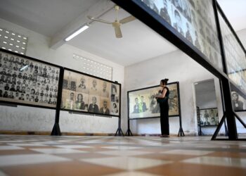 PELANCONG melihat potret mangsa-mangsa kekejaman rejim Khmer Rouge di Phnom Penh, Kemboja. – AFP