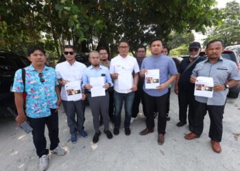 MOHD. Fitri Asmuni (tiga dari kiri) menunjukkan laporan polis yang dibuat di Ibu Pejabat Polis Daerah (IPD) Ipoh hari ini. - UTUSAN