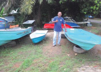 Faizal Amirul Salehodin menunjukkan isyarat bagus di samping beberapa bot gentian kaca yang telah disiapkan di Kampung Gelam, Tanjong Kling, Melaka. – UTUSAN/AMRAN MULUP