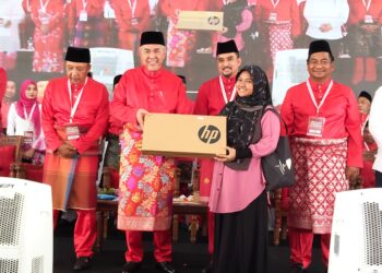 AHMAD  Zahid Hamidi (dua kiri) menyerahkan sumbangan komputer riba kepada pelajar cemerlang selepas merasmikan Mesyuarat Agung UMNO Bahagian Tanah Merah, Kelantan-UTUSAN/YATIMIN ABDULLAH.