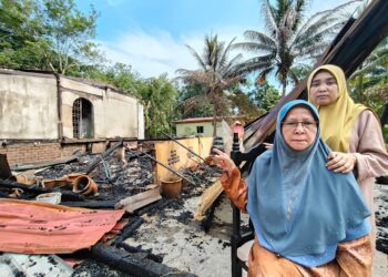 RAHMAH Omar (duduk) bersama anaknya menunjukkan rumah mereka yang terbakar di Kampung Tok Uban, Pasir Mas, Kelantan-UTUSAN/YATIMIN ABDULLAH.