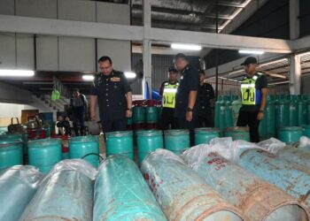 MOHD. Hazimin Jamaludin (kiri) memeriksa LPG bersubsidi yang dirampas dalam serbuan di sebuah stor di Malim Jaya, Melaka. - UTUSAN/MUHAMMAD SHAHIZAM TAZALI
