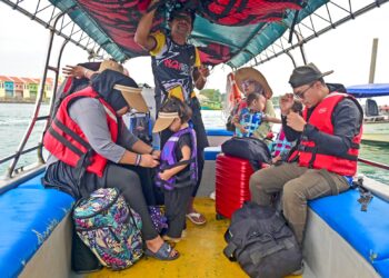 SEORANG wanita memakaikan jaket keselamatan kepada anaknya ketika menaiki bot di Jeti Pulau Kapas, Terengganu, semalam. – UTUSAN/PUQTRA HAIRRY