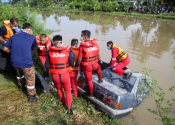 ANGGOTA Jabatan Bomba bertungkus lumus mengeluarkan mayat enam mangsa lemas dari dalam kereta yang dinaiki mereka yang tenggelam di dalam Sungai Korok di Jitra, Kedah, semalam.-UTUSAN/ SHAHIR NOORDIN