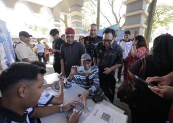 KAMALLUDIN Ismail melihat orang ramai mendaftar aplikasi mobil Skim Penstabilan Harga Minyak Masak (eCOSS) ketika sesi Walkabout PJRM KPDN Perak di Bangunan Persekutuan di Ipoh hari ini. - UTUSAN