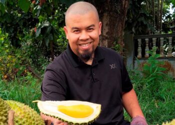 AHMAD Maher Safiain menunjukkan durian Musang King yang dijual kepada pelanggan di bekalang Masjid Jamek Al-Sultan Ismail Petra, Kubang Kerian, Kelantan. – UTUSAN/YATIMIN ABDULLAH