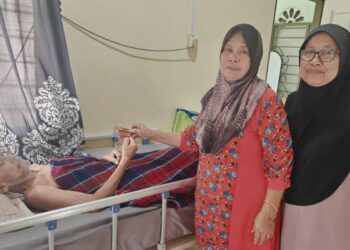 ROSLI Mahat yang terlantar sakit bersama isterinya, Che Putes Mohamad Ariff (tengah) memegang kad mesin juruwang automatik (ATM) yang baharu diperoleh di kediaman mereka di Felda Tersang 1 di Raub, Pahang.