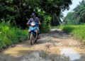 PENDUDUK menunjukkan keadaan jalan yang rosak di Kampung Batu Hitam, Pasir Salak, Perak. – UTUSAN/AIN SAFRE BIDIN