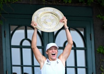 Iga Swiatek meraikannya dengan trofi pemenang, Venus Rosewater Dish, sambil menunjukkannya kepada orang ramai dari balkoni Gelanggang Tengah selepas memenangi perlawanan tenis terakhir perseorangan wanitanya menentang pemain AS Amanda Anisimova pada Kejohanan Wimbledon 2025, hari ini. - AFP
