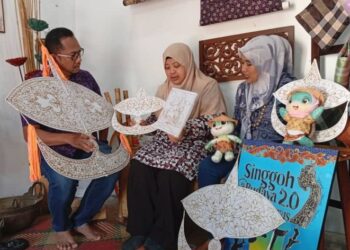 SARINAH Said ( tengah) menunjukkan rangka wau bulan dan kit mewarna batik yang dieksport ke Singapura di Lambo Sari yang terletak di Kampung Telaga Daing, Terengganu.- UTUSAN/ ERMA YUSNIDA JUSOH