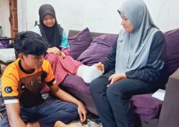 ZAILAWATI Ismail (kanan) memeriksa keadaan kaki anak perempuannya yang patah di rumah sewanya di Felda Jerangau, Dungun, Terengganu.
– UTUSAN/NIK NUR IZZATUL HAZWANI NIK ADNAN