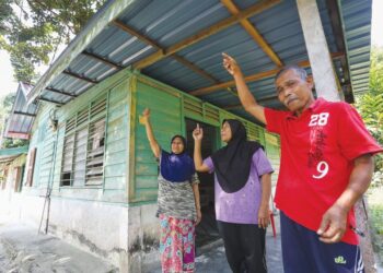 PAINAH Ismail dan abangnya, Kamarudin Ismail menunjukkan bumbung rumah keluarga mereka yang diganti baharu oleh Yayasan Perak di Kampung Jawa, Tapah Road, Tapah. – UTUSAN/MUHAMAD NAZREEN SYAH MUSTHAFA