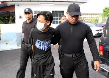 TERTUDUH (kiri) semasa dibawa oleh anggota polis untuk prosiding perbicaraan di Mahkamah Majistret Tanah Merah, Kelantan hari ini-UTUSAN/KAMARUL BISMI KAMARUZAMAN.