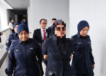 TERTUDUH diiringi anggota polis ketika dihadapkan ke Mahkamah Majistret Ayer Keroh, Melaka atas pertuduhan menyebar, mengugut dan menyimpan gambar lucah seorang wanita. - UTUSAN/MUHAMMAD SHAHIZAM TAZALI